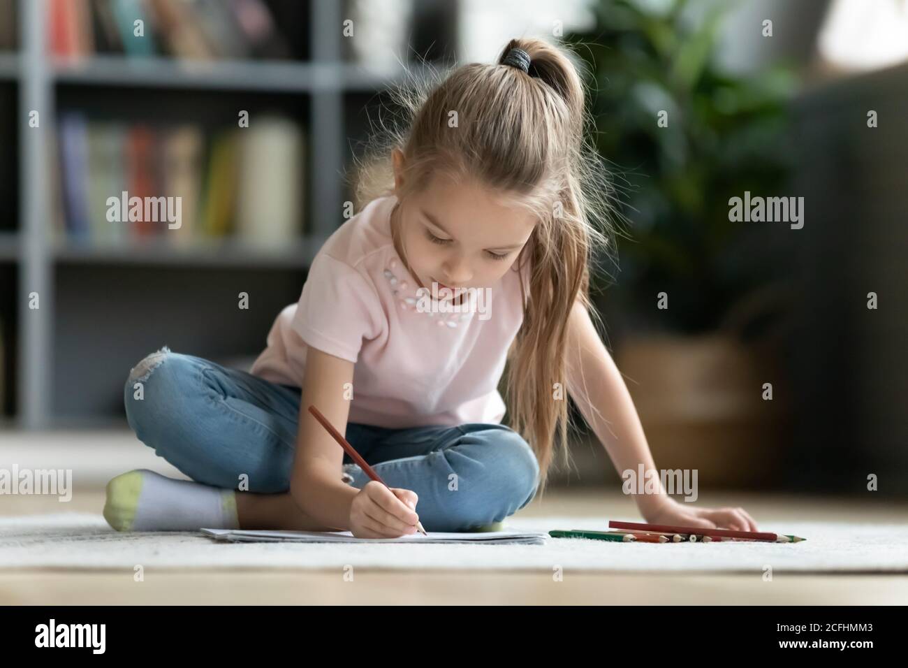 Bella bambina che gioca a pavimento caldo, disegnando con matite Foto Stock