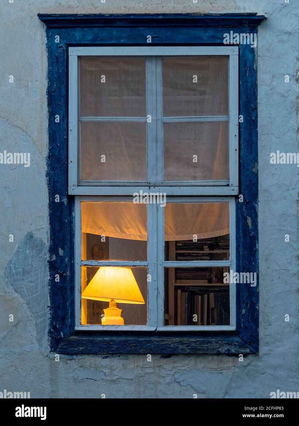 Lampada a luce calda e libri in biblioteca attraverso una cornice di  finestra blu-e-bianco, Hydra Island, Grecia Foto stock - Alamy
