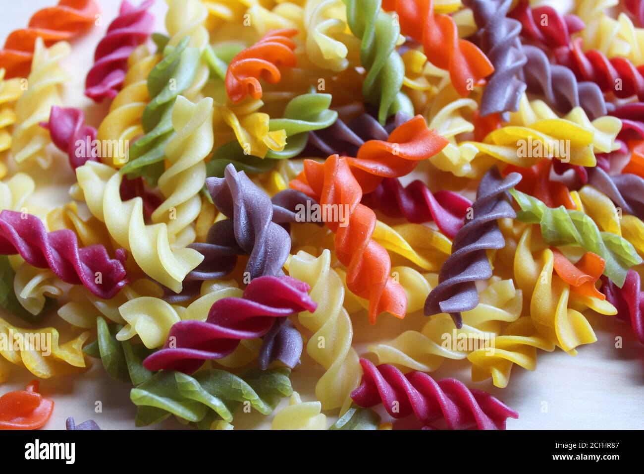 Festosa pasta a spirale di fusilli multicolore su fondo bianco Foto Stock