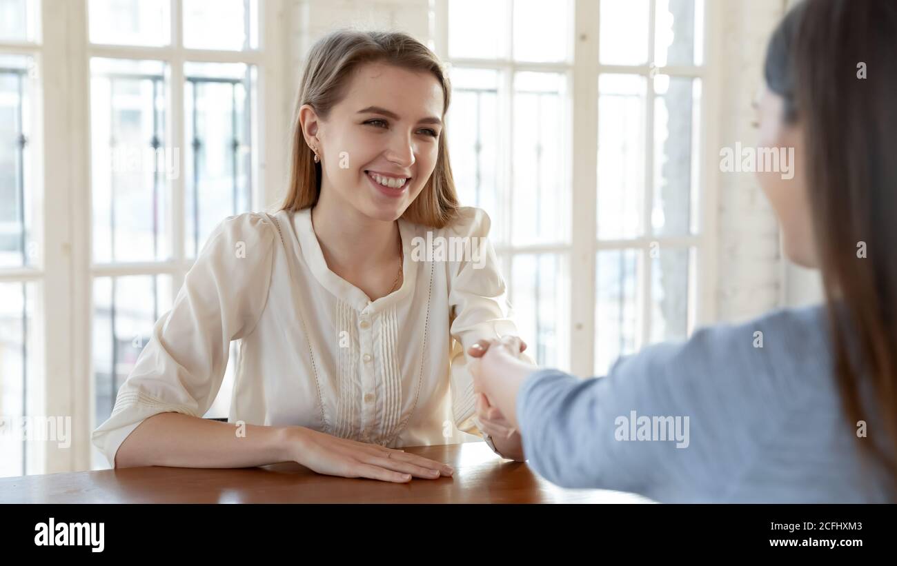 Sorridente candidato giovane donna di successo scuotendo la mano del datore di lavoro del reclutatore Foto Stock