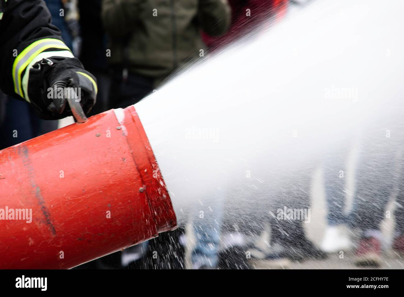 Fornitura di schiuma dal generatore di schiuma, schiuma antincendio vola dal generatore di schiuma, che mantiene il vigile del fuoco in abiti da combattimento Foto Stock