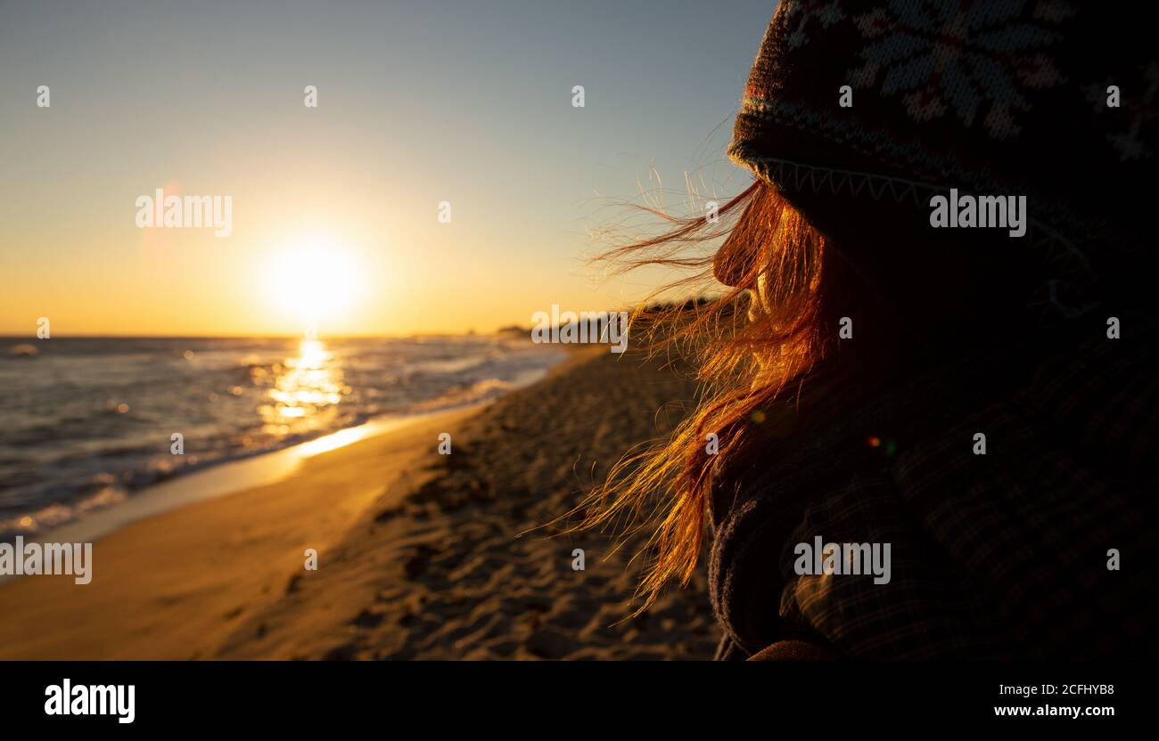 Il viaggiatore donna guarda il mare all'alba. I suoi capelli si flutters nel vento Foto Stock