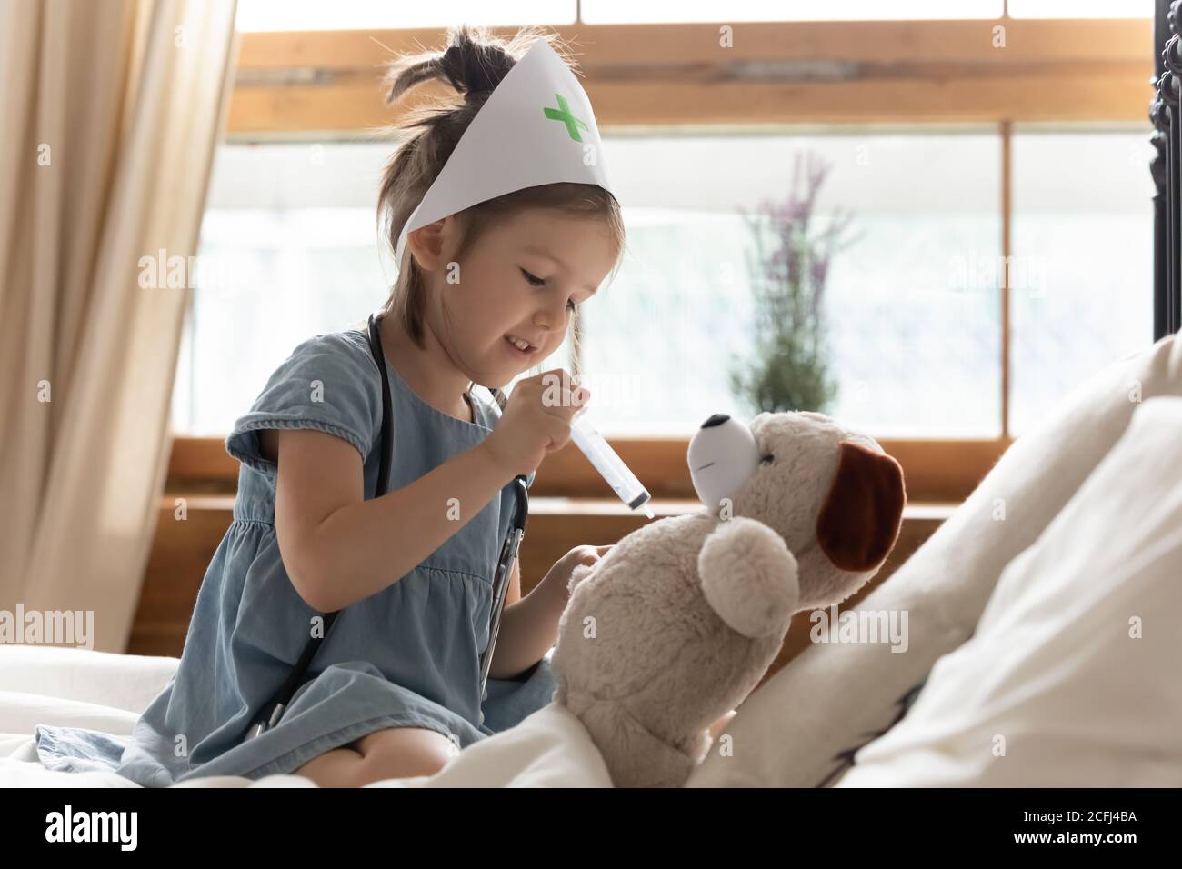 La ragazza gioca tenendo la siringa che dà l'iniezione al giocattolo morbido dell'animale Foto Stock