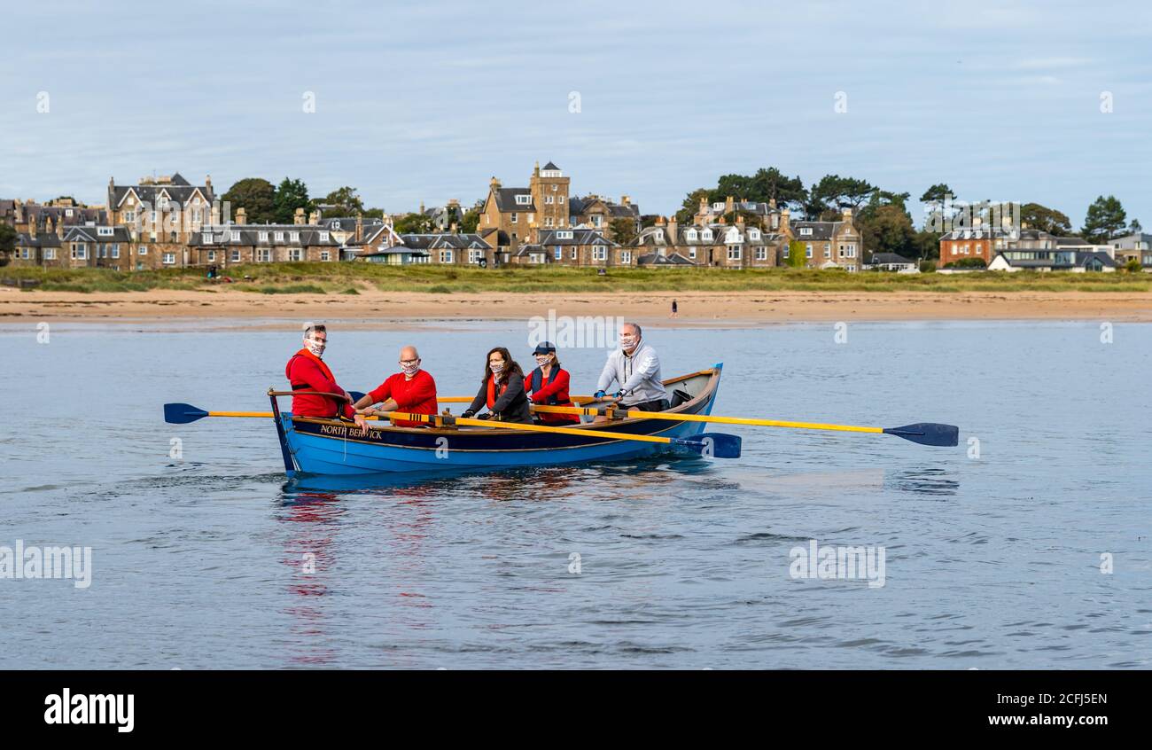 North Berwick, East Lothian, Scozia, Regno Unito, 6 settembre 2020. Fila inaugurale post-lockdown: I membri del club costiero NB si sono stabiliti questa mattina da West Bay per la prima volta dal blocco di marzo. Le misure di sicurezza Covid sono in atto, compresi i vogatori che indossano maschere per il viso. L'equipaggio si fila fuori da West Bay nella città di mare Foto Stock