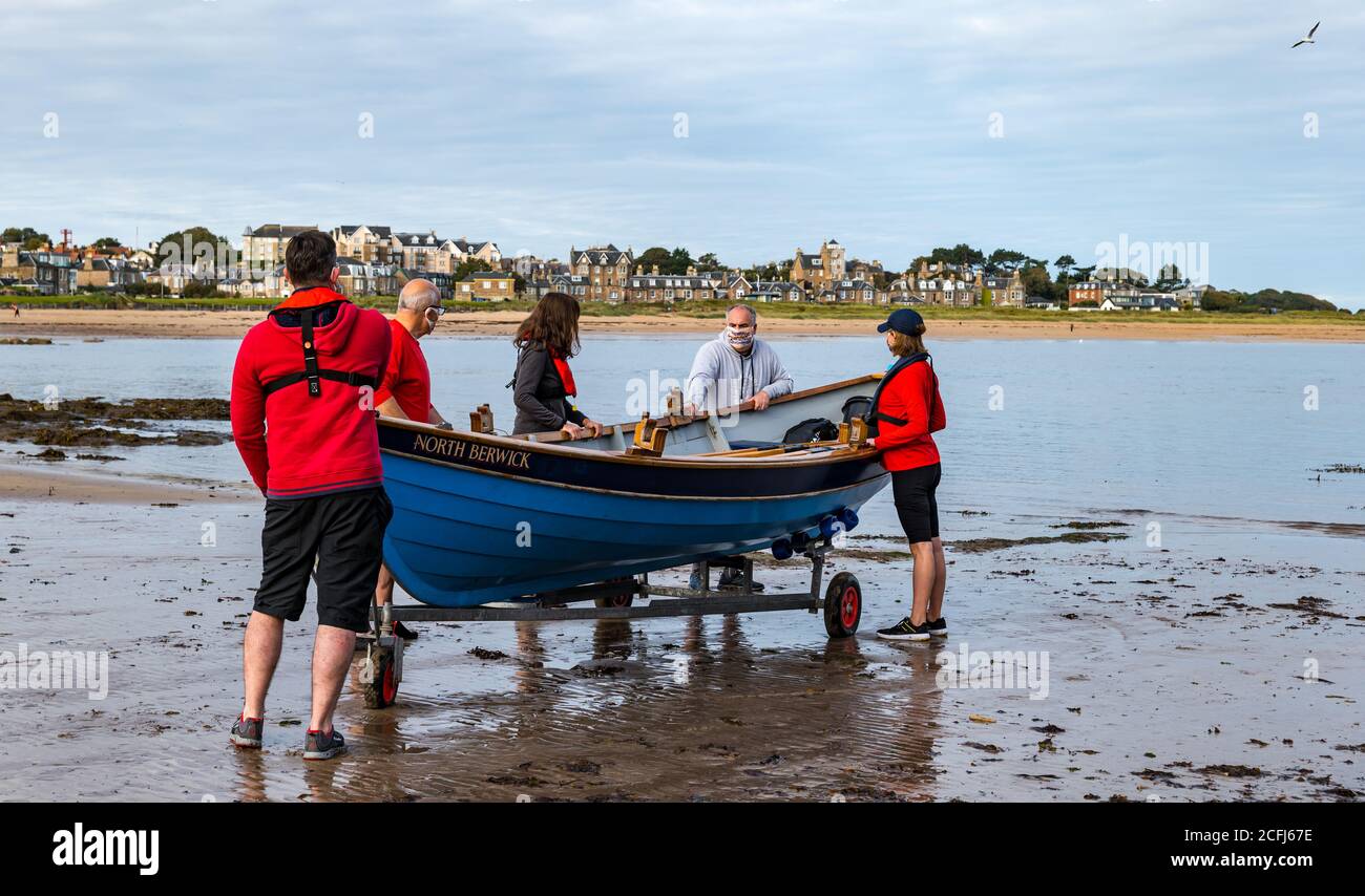 North Berwick, East Lothian, Scozia, Regno Unito, 6 settembre 2020. Fila inaugurale post-lockdown: I membri del club costiero NB si sono stabiliti questa mattina da West Bay per la prima volta dal blocco di marzo. Le misure di sicurezza Covid sono in atto, compresi i vogatori che indossano maschere per il viso. L'equipaggio lancia lo skiff di Sr Ayle nel Firth of Forth Foto Stock