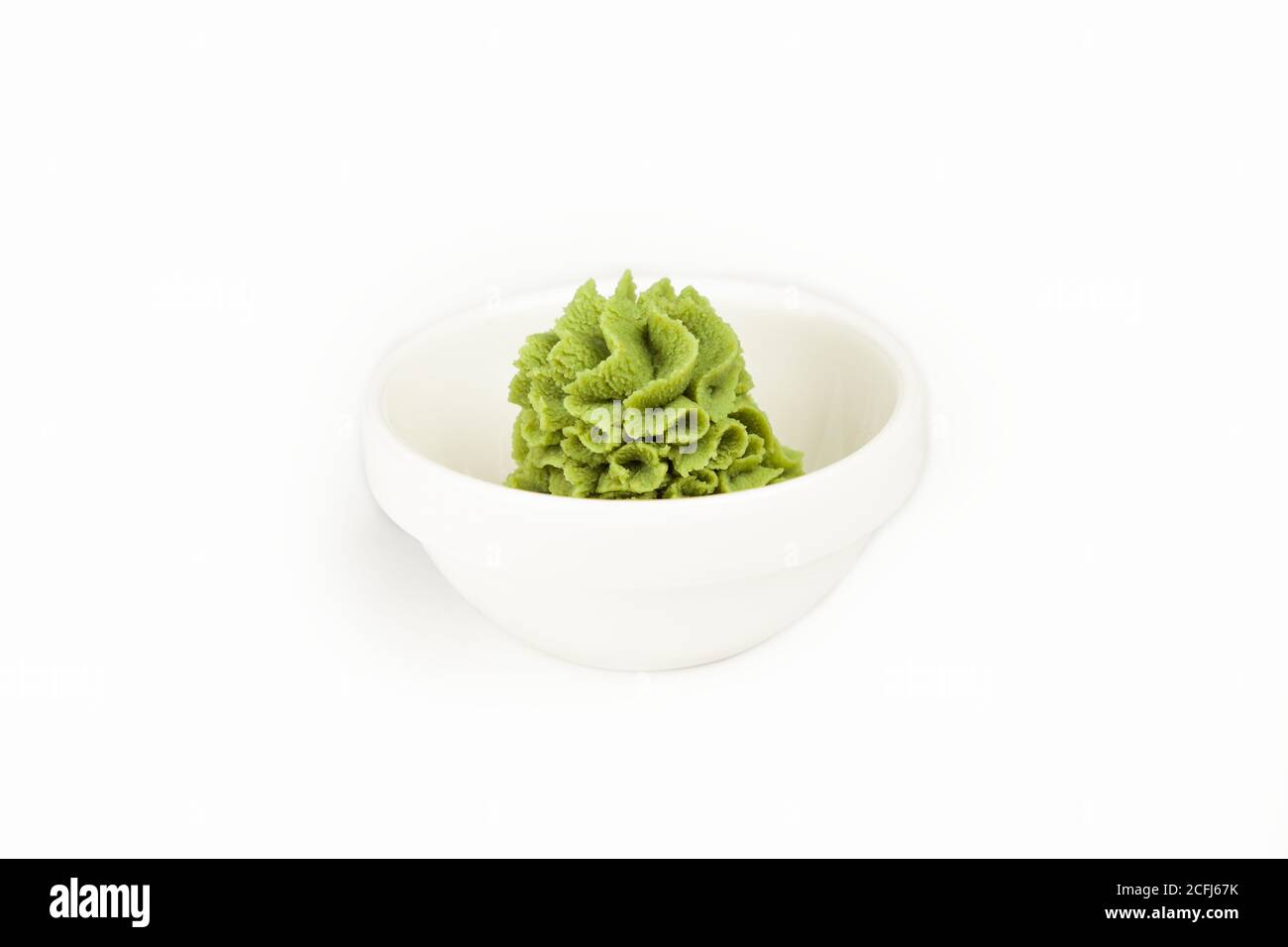 Ciotola con salsa wasabi su un piatto bianco. Per il menu del ristorante. Piatto di condimento tradizionale cinese classico wasabi. Cucina giapponese, pasta di rafano. Foto Stock