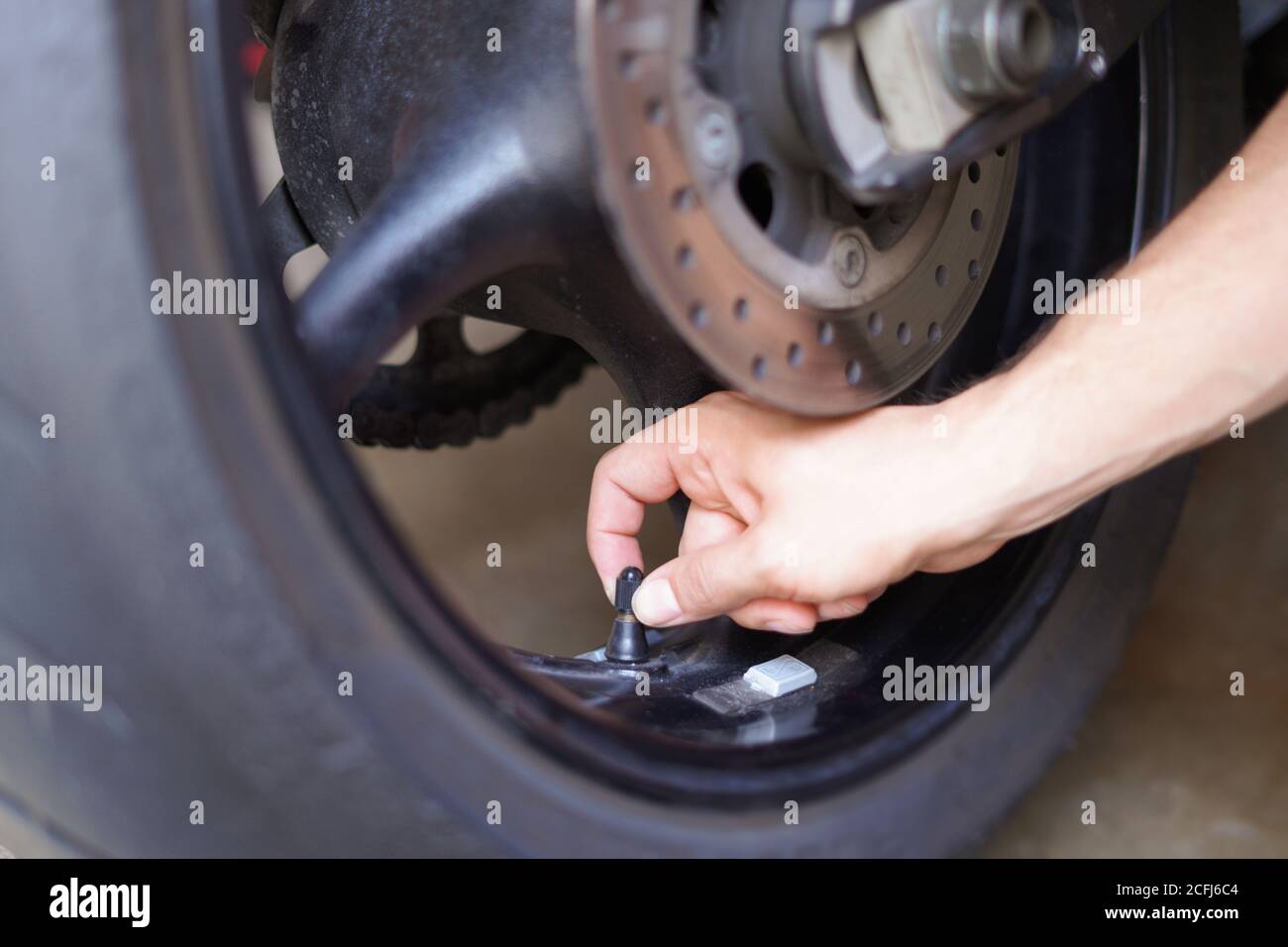 Uomo che controlla manualmente la pressione dell'aria della ruota del motociclo prima di procedere Foto Stock