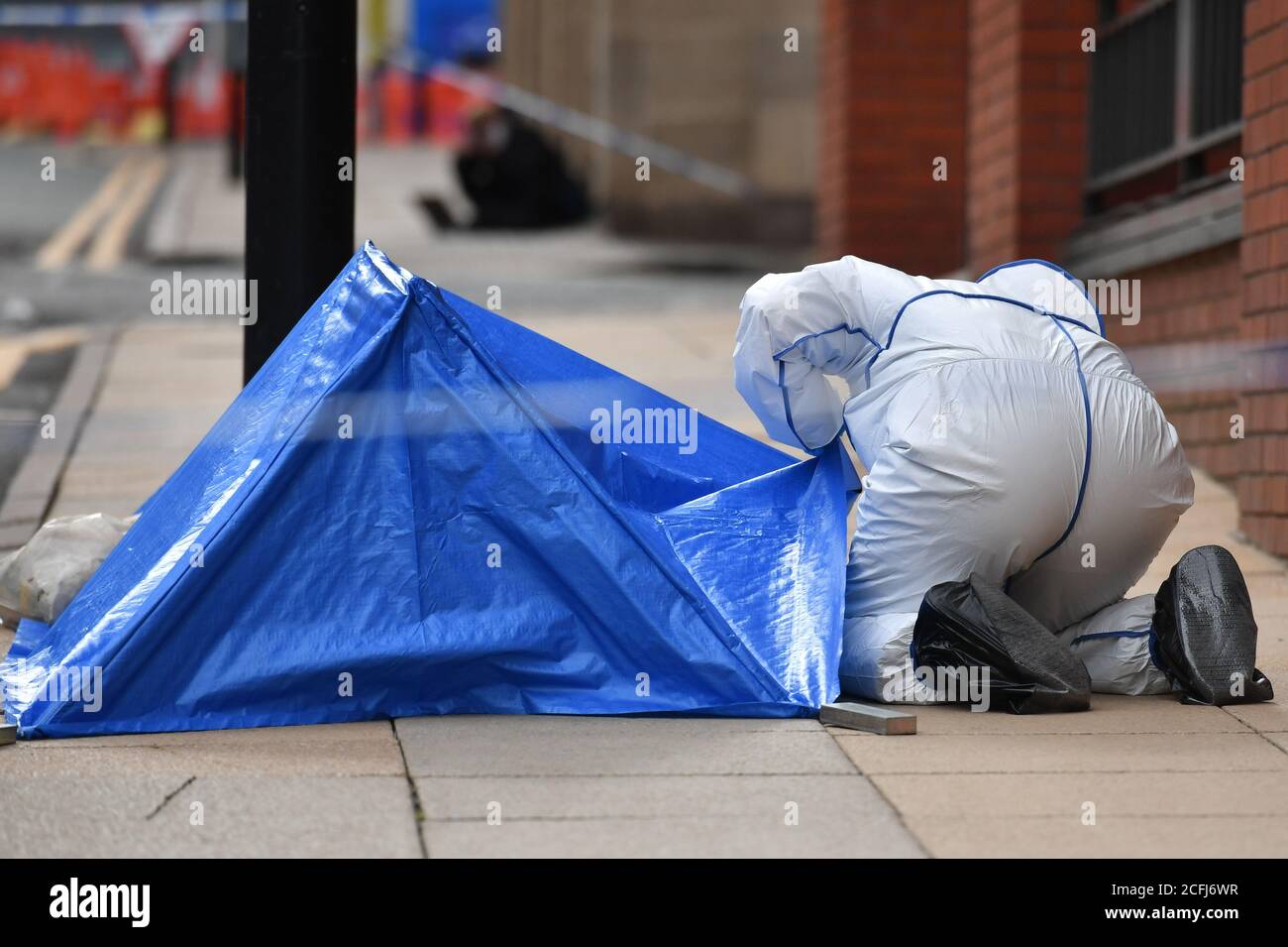 Un ufficiale di polizia forense si occupa di una piccola tenda di polizia blu che copre un'area di marciapiede in Livery Street a Birmingham dopo che un certo numero di persone sono state pugnate nel centro della città. La polizia delle Midlands occidentali ha detto che sono stati chiamati a segnalare un pugnalato intorno alle 12.30 di domenica e un certo numero di altri pugnali sono stati segnalati nella zona intorno allo stesso tempo. Foto Stock