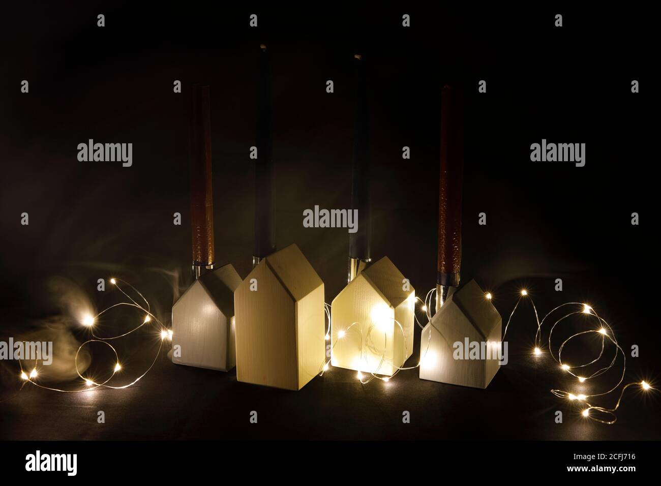 Advent decorazione con piccole case, luci e candele nel buio Foto Stock