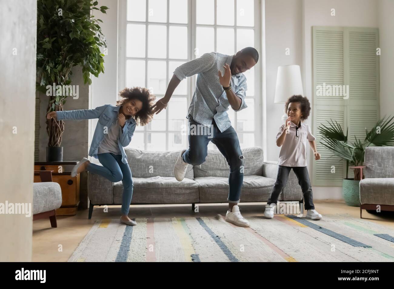 Felice padre afroamericano che mostra divertenti mosse di ballo ai bambini. Foto Stock