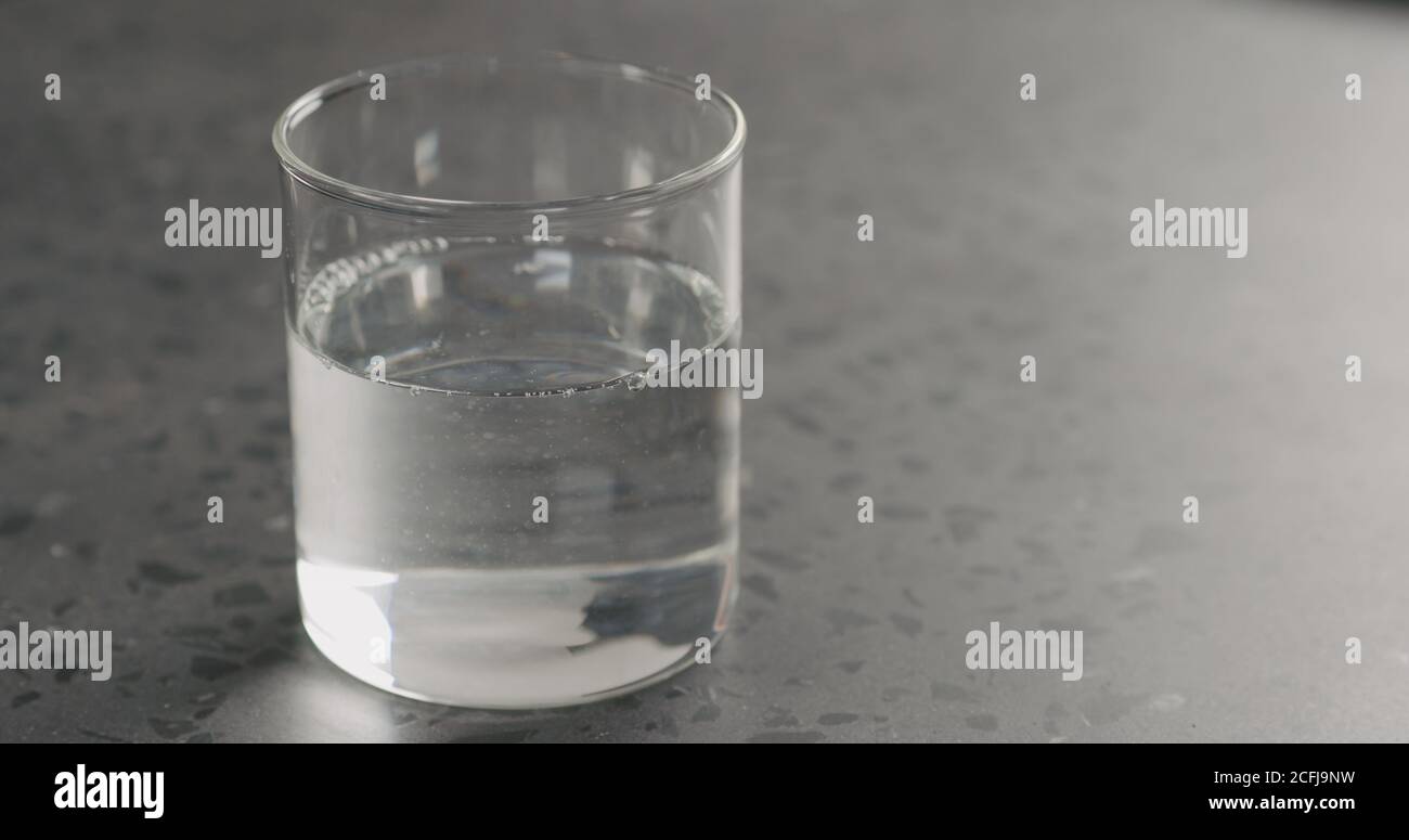 pulire l'acqua fresca nel bicchiere di vetro sul piano di cemento, foto larga Foto Stock