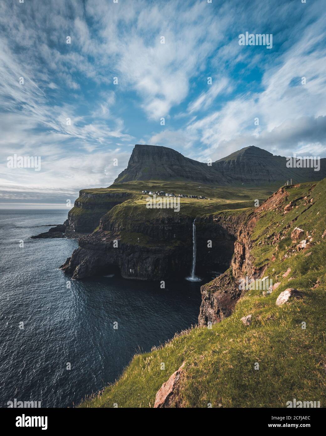 Gasadalur villaggio e Mulafossur la sua cascata iconica durante l'estate con il cielo blu. Vagar, Isole Faroe, Danimarca. Scorgo nel nord atlantico Foto Stock