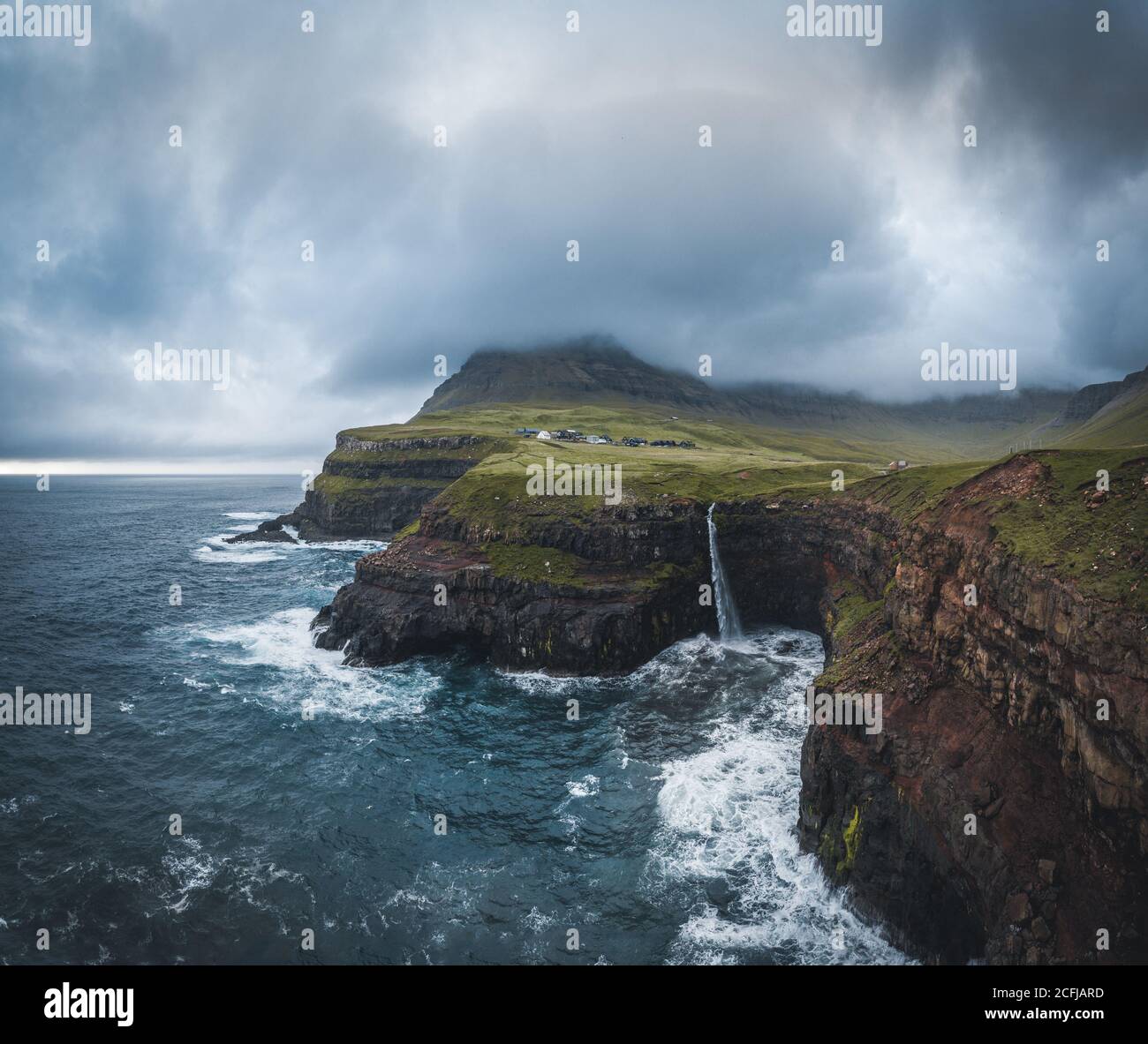 Panorama del drone aereo del villaggio di Gasadalur e Mulafossur la sua cascata iconica, Vagar, Isole Faroe, Danimarca. Vista approssimativa nell'oceano atlantico settentrionale Foto Stock