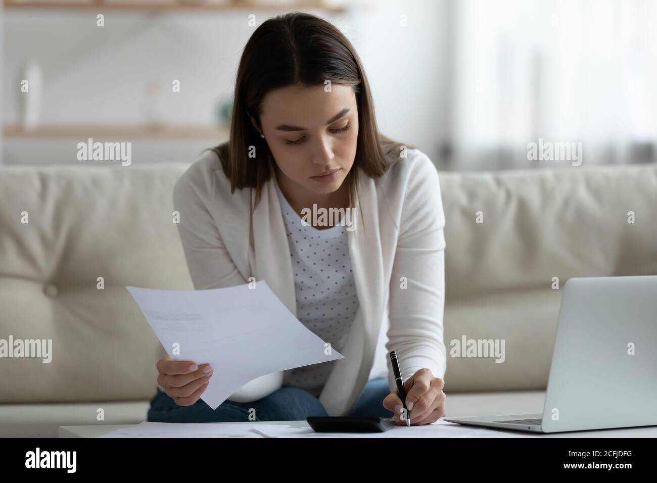 Focalizzato giovane donna che pianifica i pagamenti ipotecari a casa. Foto Stock