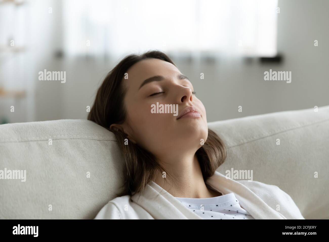 La testa ha girato la donna millenaria stanca appoggiandosi su un divano accogliente. Foto Stock