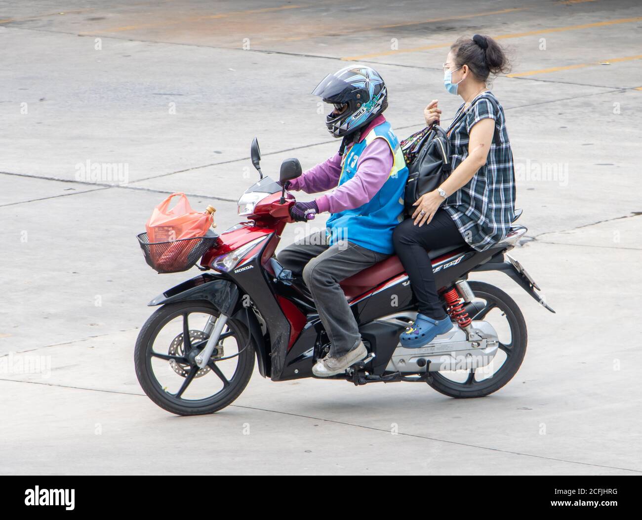 SAMUT PRAKAN, THAILANDIA, 03 2020 LUGLIO, UN tassista su una moto giri con una donna e le sue borse shopping. Il conducente del mototaxi trasporta un passeggero. Foto Stock