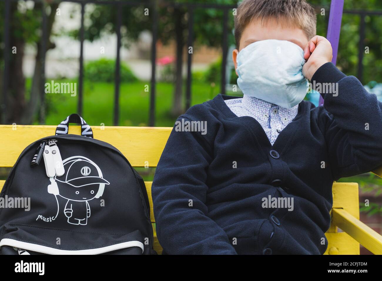 bambino ragazzo che indossa una maschera chirurgica per la prevenzione del coronavirus. Ritorno a scuola. Ritratto di bambino con borsa in attesa di un bus scolastico. Nuovo normale. Guarire Foto Stock