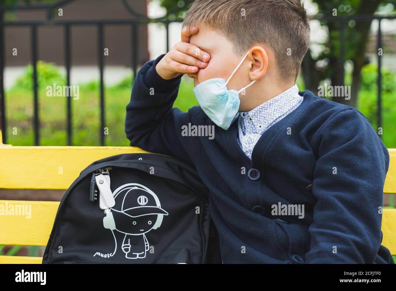 ragazzo triste che indossa una maschera facciale per la prevenzione del coronavirus. Ritorno a scuola. Ritratto di un bambino stanco in attesa di un bus scolastico. Nuovo normale. Salute med Foto Stock