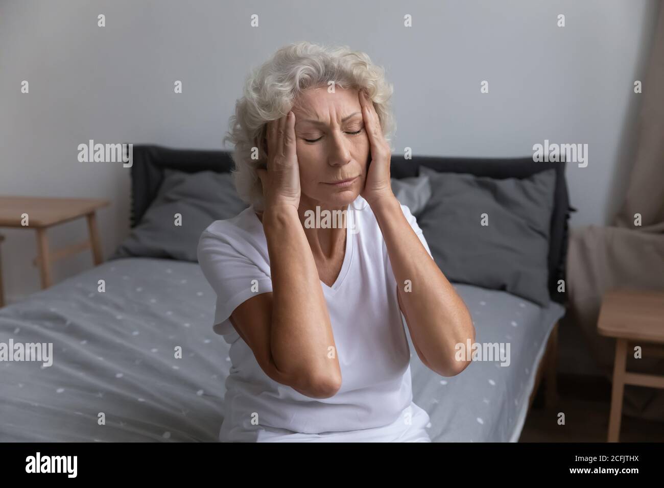 Infelice donna matura malsana che tocca templi, che soffrono di mal di testa Foto Stock