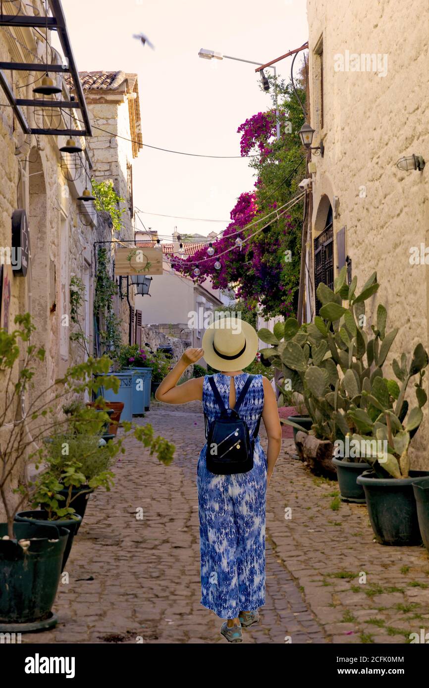 Giovane donna che cammina in una strada stretta ad Alacati, Cesme Turchia Foto Stock