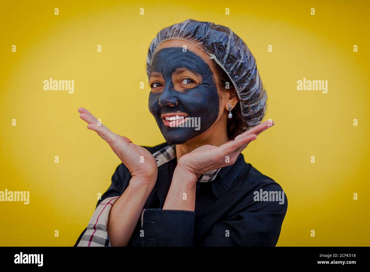 Donna con maschera di fango e felice espressione che mostra palme Foto Stock