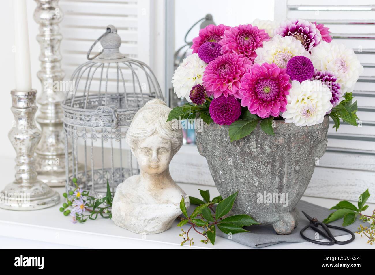 decorazione vintage con bouquet di fiori di dahlia in rosa e bianco, busto donna e gabbia di uccelli Foto Stock