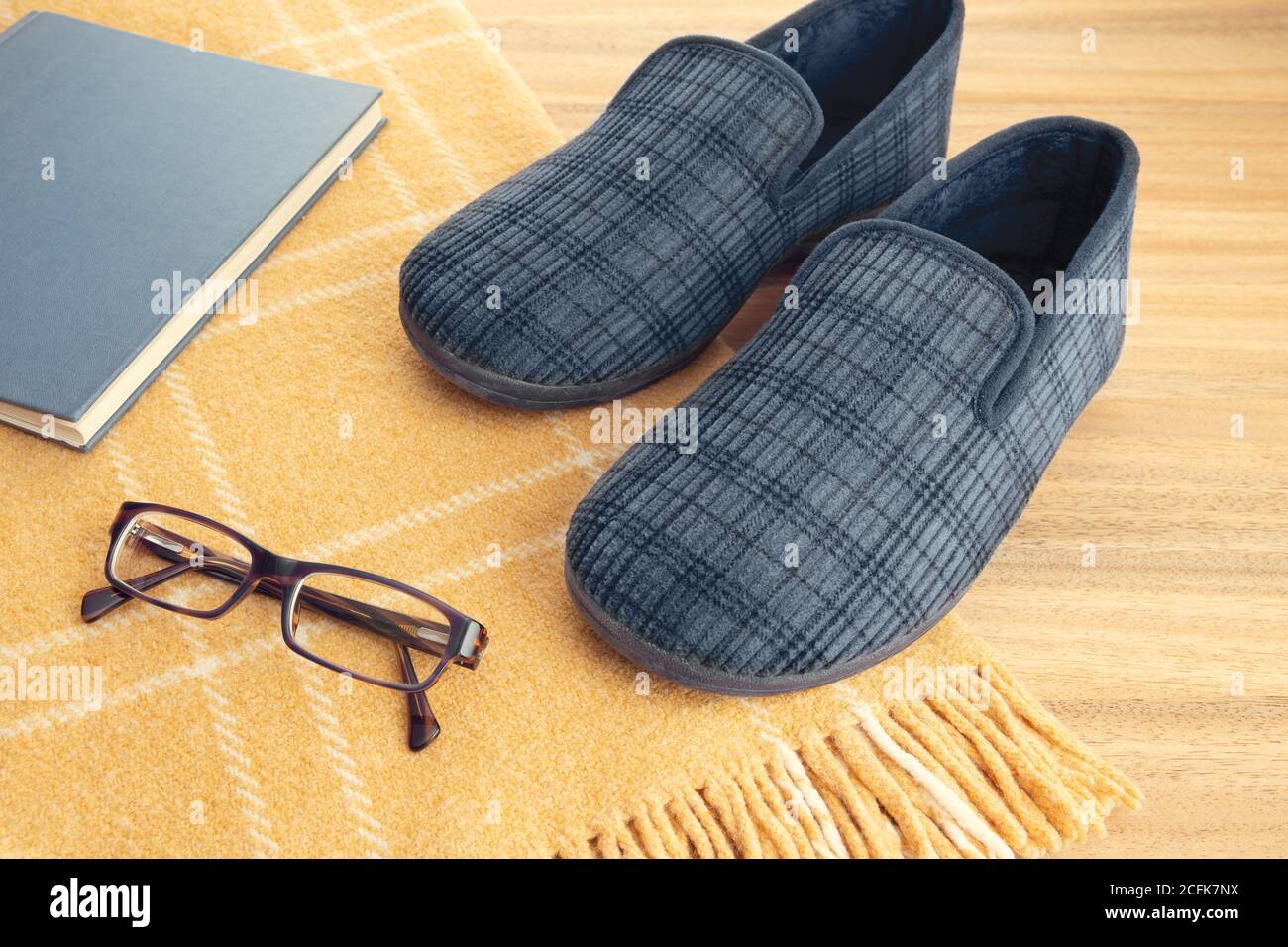 Pantofole domestiche, libro, occhiali e coperta di lana. Home relax in inverno concetto Foto Stock