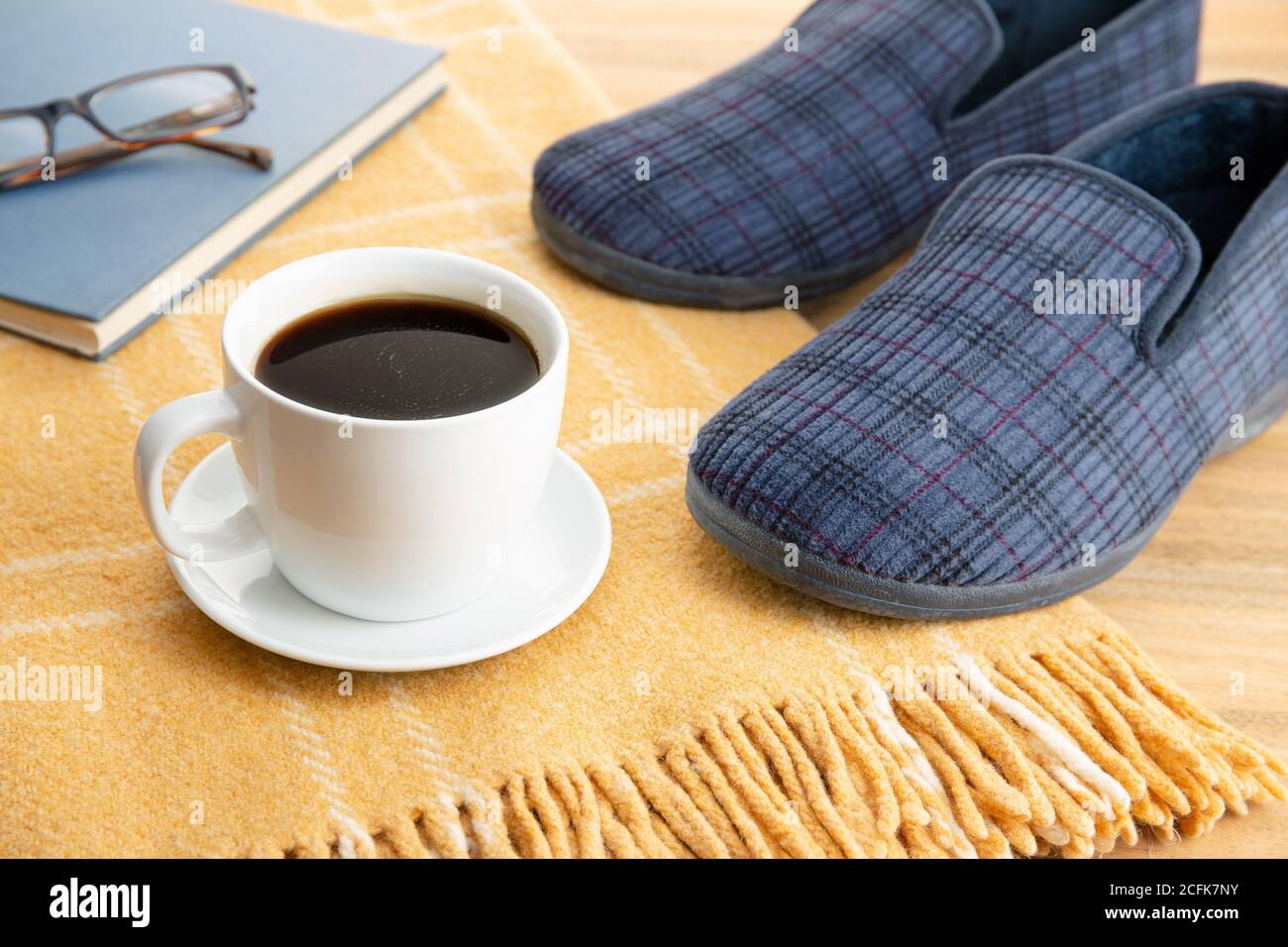 Ciabatte per la casa maschile, caffè, libro e coperta di lana. Home relax in inverno concetto Foto Stock