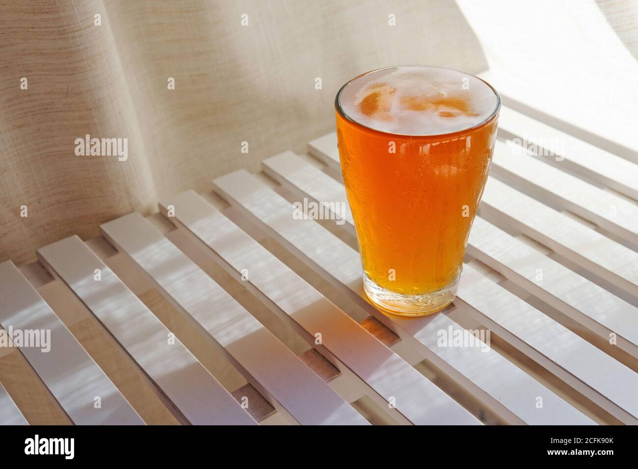 Ampio angolo di vetro lucido con birra fresca inserita tavolo in legno in estate in giornata di sole per rinfresco Foto Stock