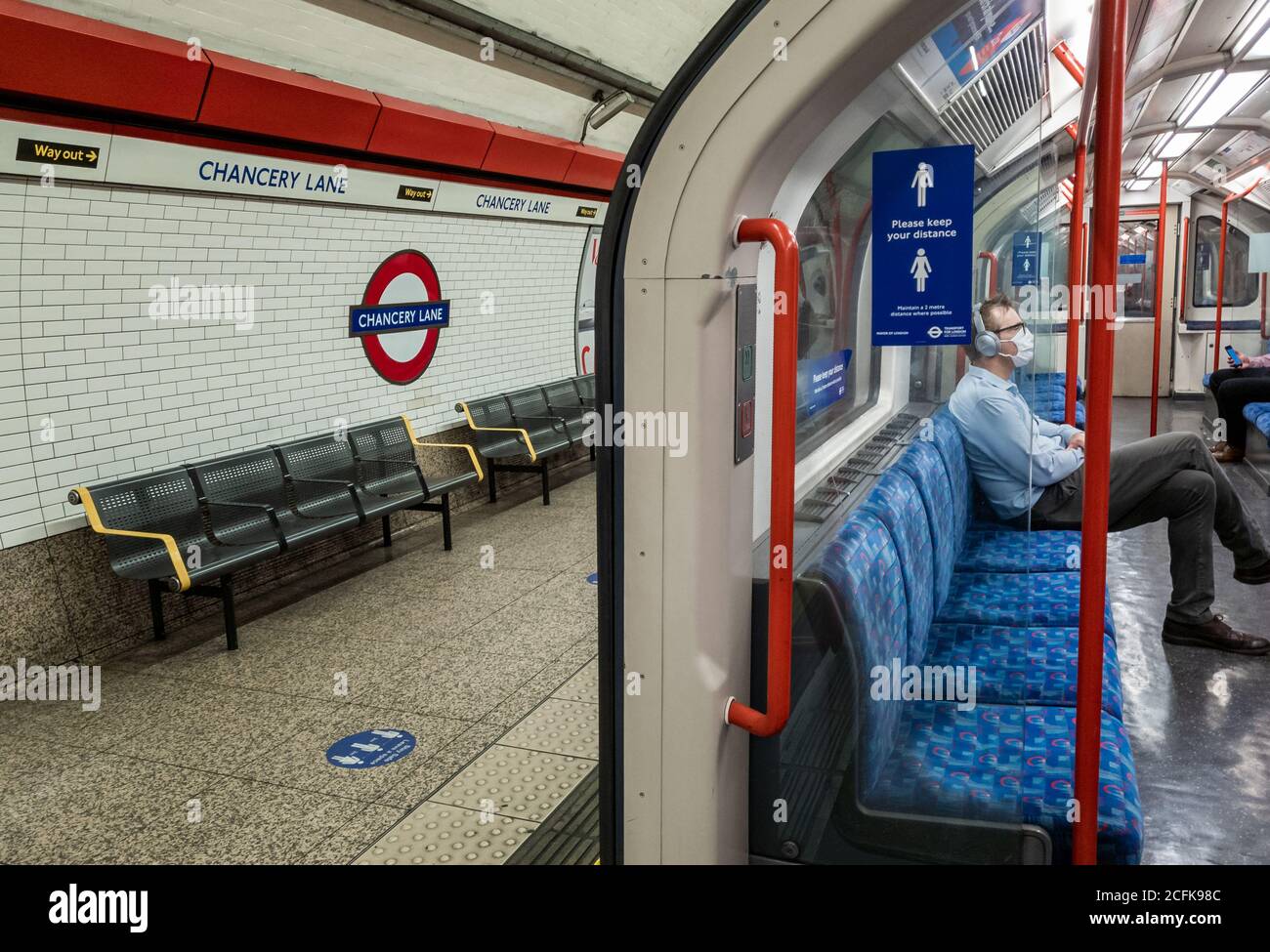 Passeggeri che utilizzano la metropolitana di Londra seguendo le norme di sicurezza del Covid-19 del governo di indossare una copertura di fronte e di distanza sociale. Foto Stock