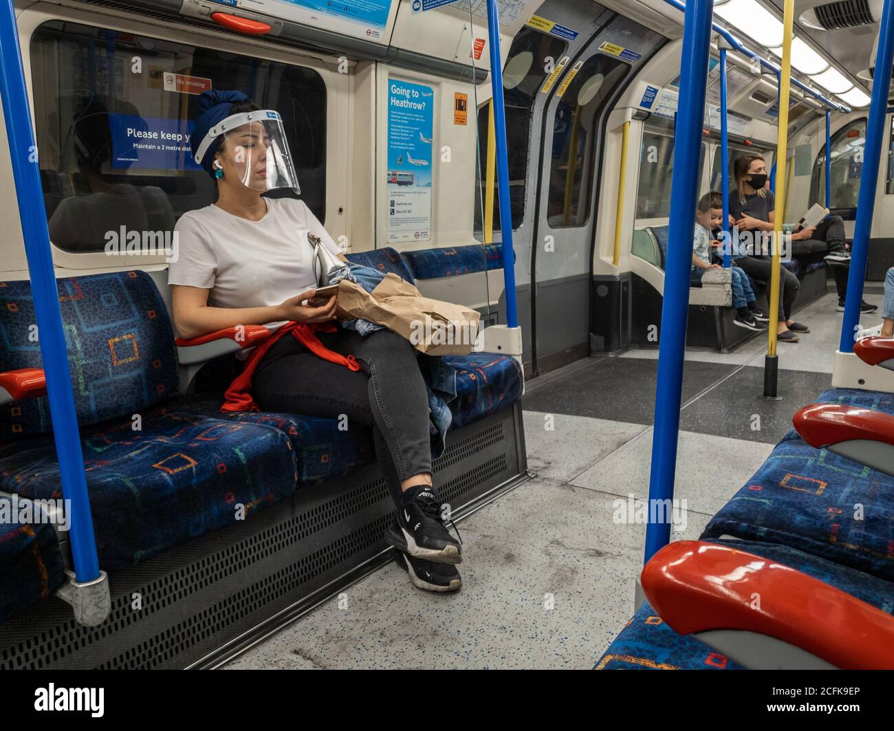 Passeggeri che utilizzano la metropolitana di Londra seguendo le norme di sicurezza del Covid-19 del governo di indossare una copertura di fronte e di distanza sociale. Foto Stock