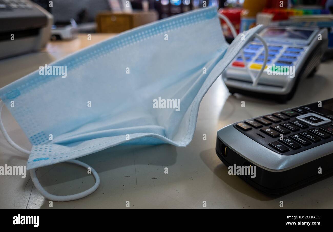 Maschera facciale o copertura facciale sul banco vendite di un rivenditore di alta strada. È un requisito legale indossare uno in tutti i negozi. Foto Stock