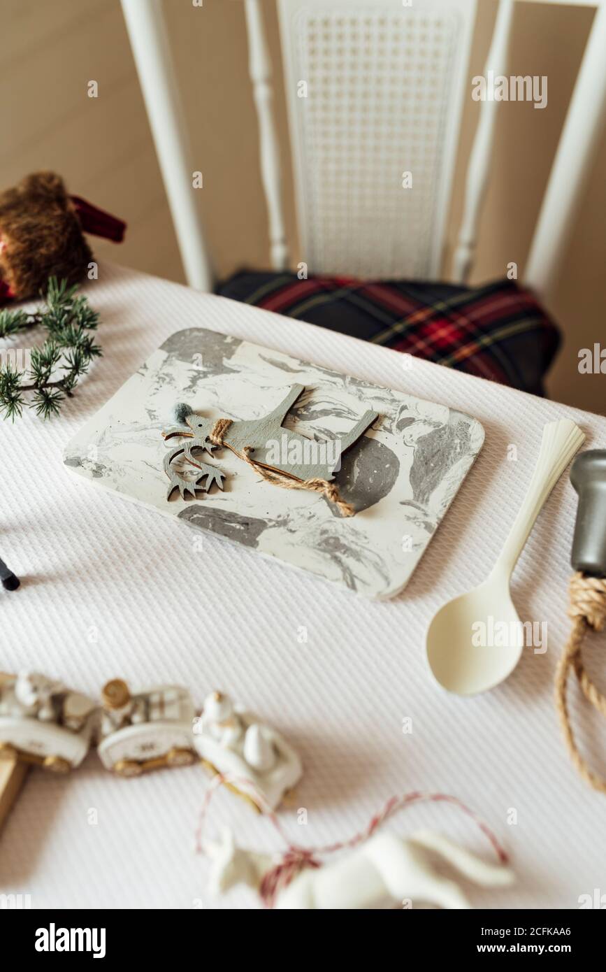 Dall'alto del tavolo festivo decorato con vari elementi natalizi e giocattoli disposti vicino utensili per la celebrazione dei bambini Foto Stock