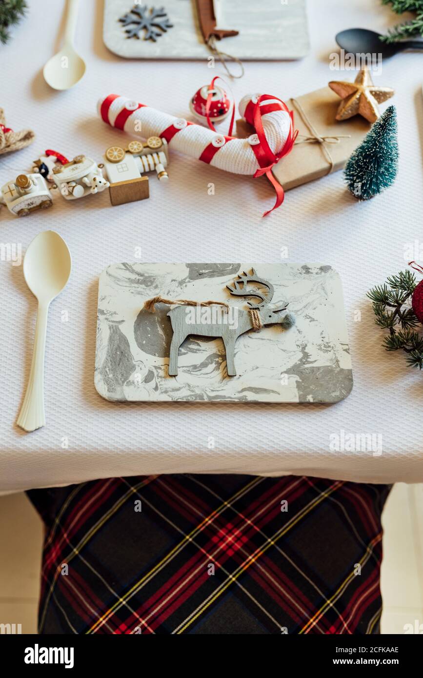 Dall'alto del tavolo festivo decorato con vari elementi natalizi e giocattoli disposti vicino utensili per la celebrazione dei bambini Foto Stock