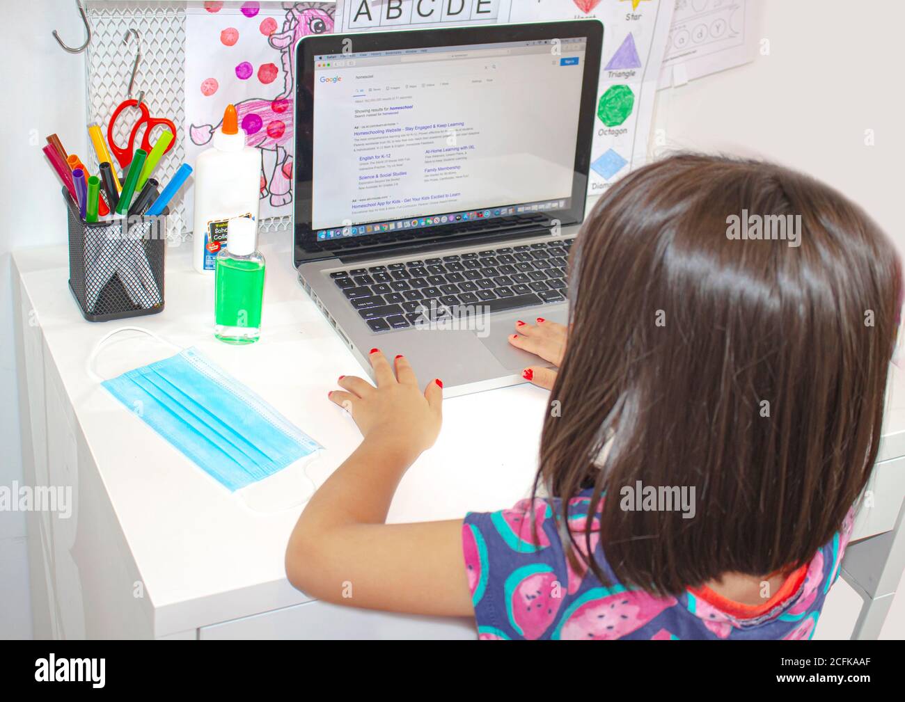 Calgary, Alberta, Canada. 5 settembre 2020. Uno studente di scuola elementare che guarda un monitor per computer con maschera facciale e disinfettante per le mani su una scrivania. Foto Stock