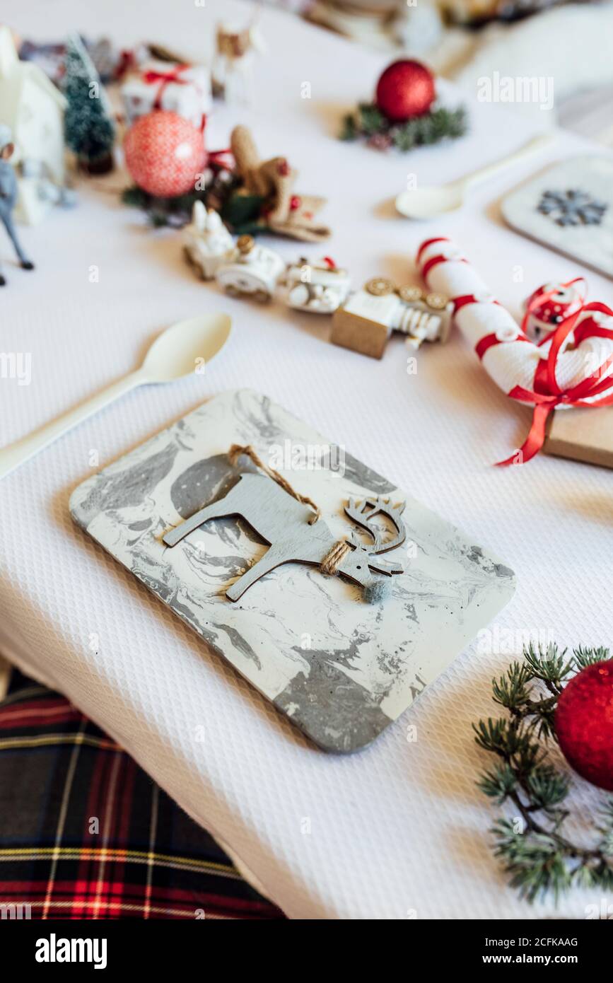 Dall'alto del tavolo festivo decorato con vari elementi natalizi e giocattoli disposti vicino utensili per la celebrazione dei bambini Foto Stock