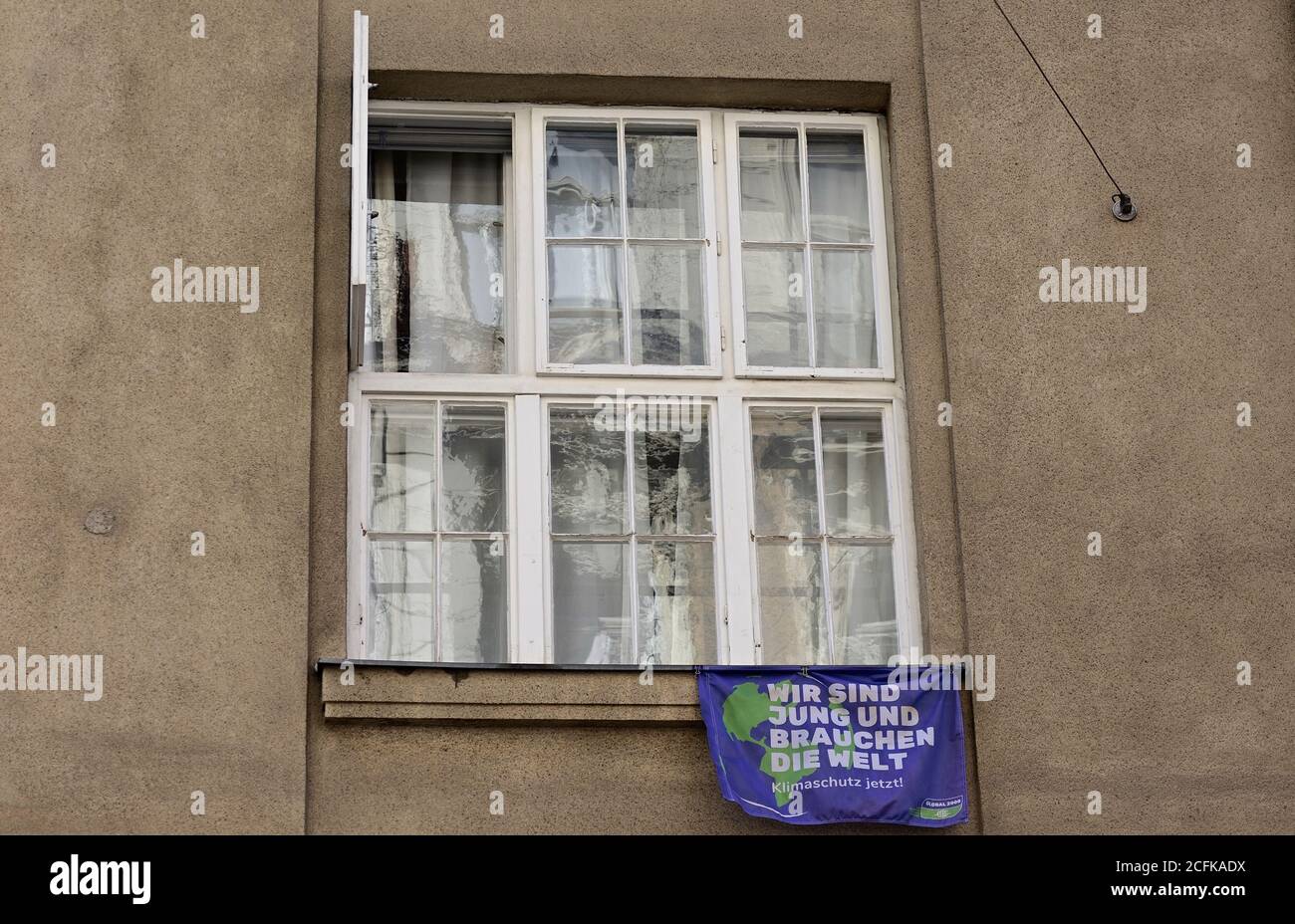 Vienna, Austria. Un banner che recita 'Siamo giovani e abbiamo bisogno del mondo. Protezione della climatizzazione." davanti a un finestrino Foto Stock