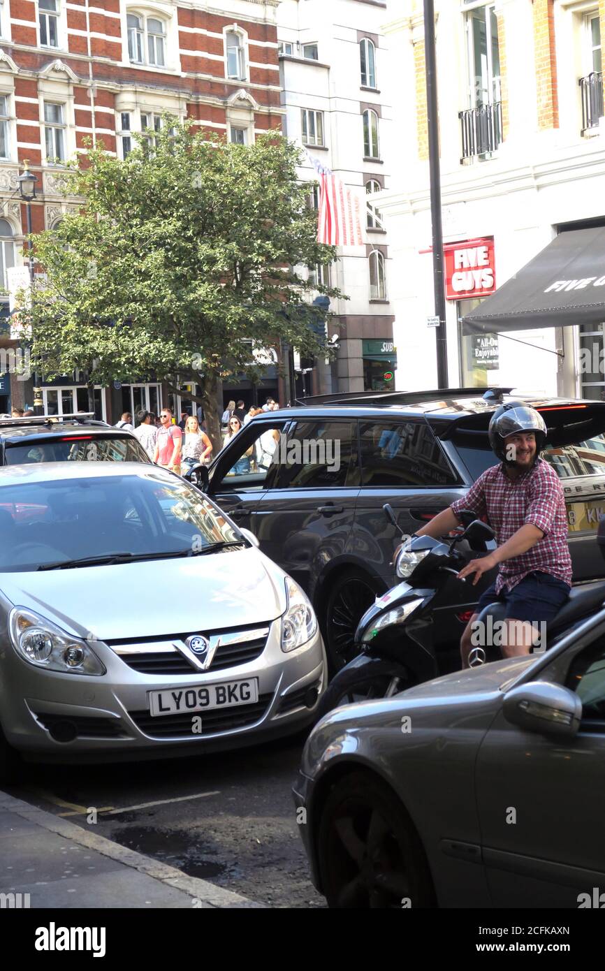 Lo scooter si sposta indietro nella congestione del traffico a Londra, Inghilterra Foto Stock