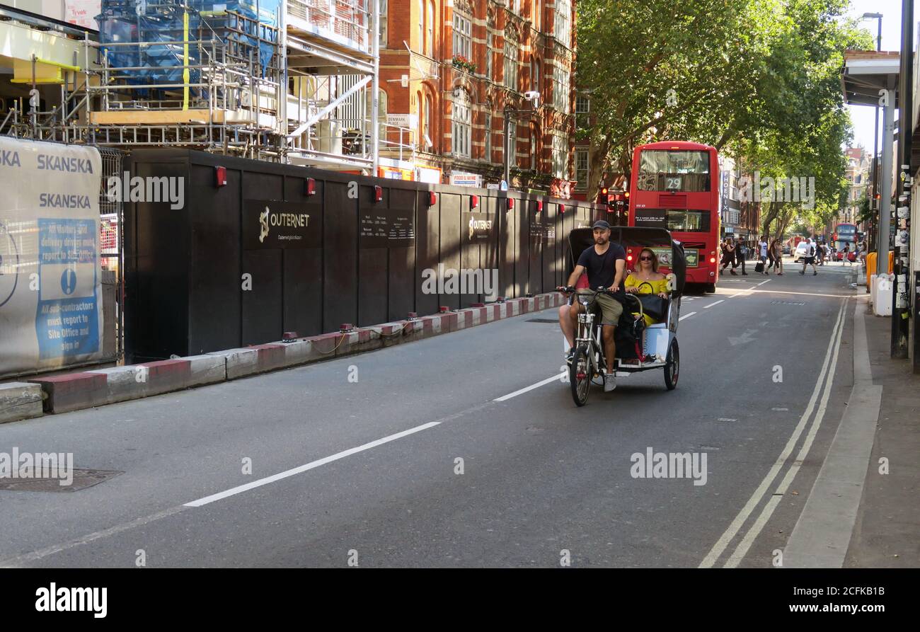 Autista pedicab con tariffa sulla Charing Cross Road di Londra Foto Stock