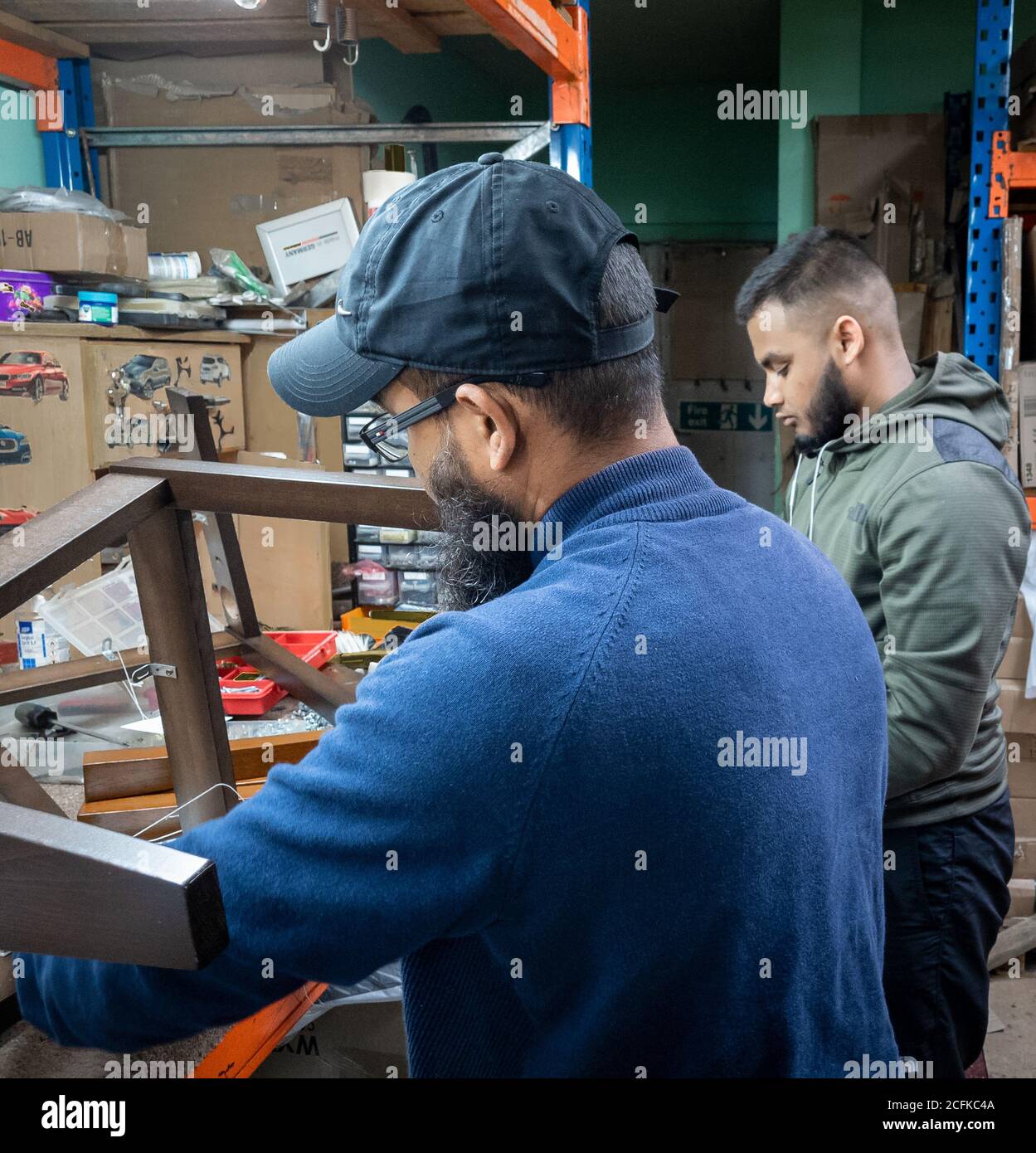Assemblatori di mobili che lavorano in un'officina, montando insieme una sedia a pacchetto piatto. Foto Stock