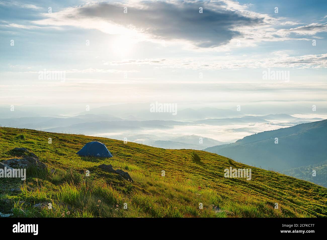 Solitaria tenda turistica alta in montagna con bella panoramica vista sulla valle della nebbia mattutina Foto Stock