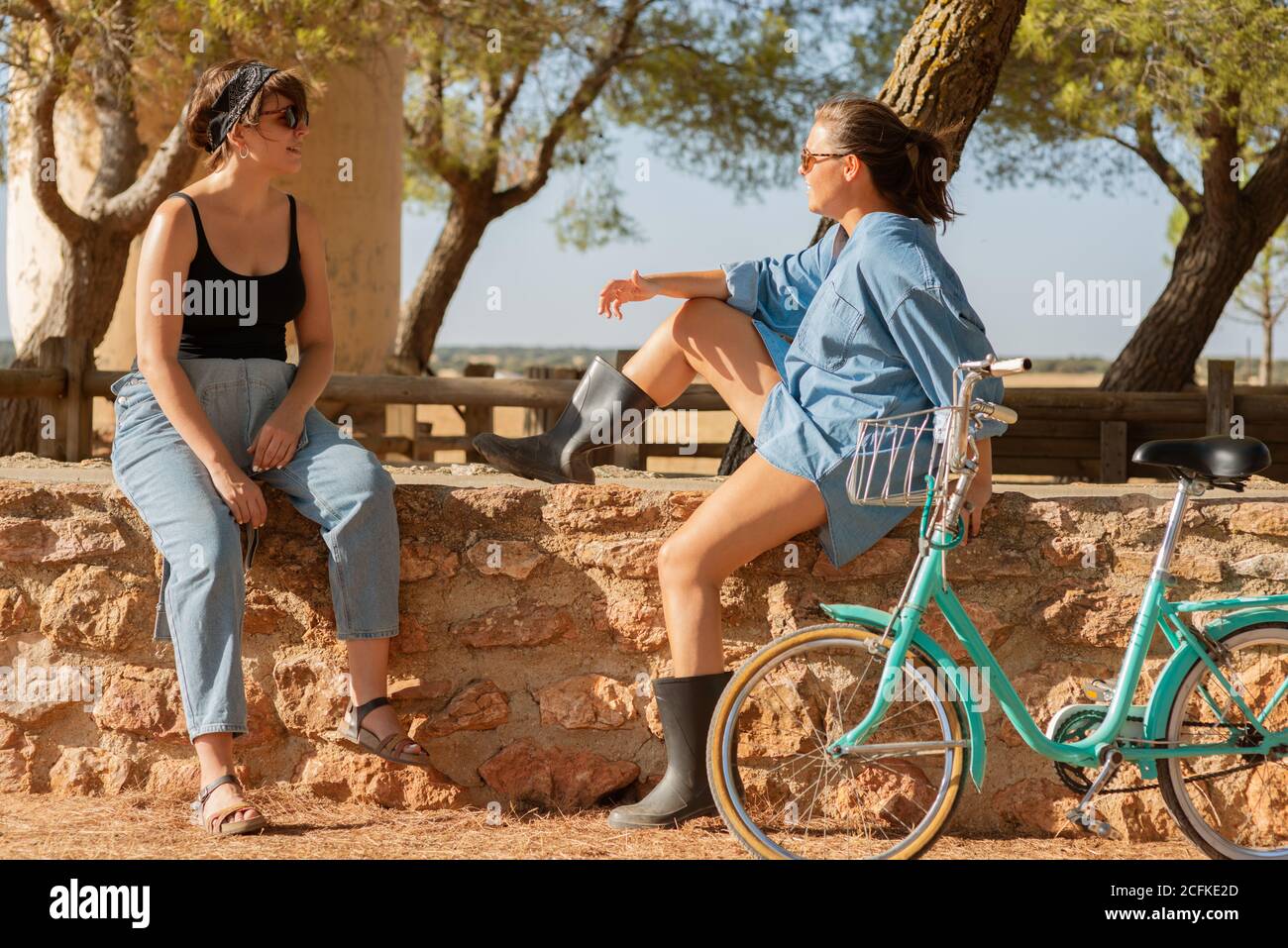 Donne positive in abiti rustici seduti in ombra e. relax in una giornata di sole in campagna Foto Stock