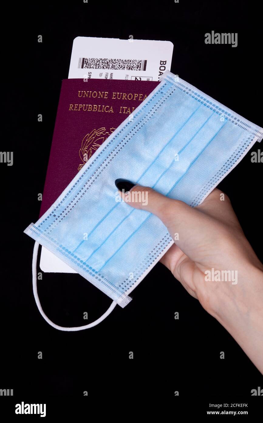 passaporto italiano e maschera chirurgica con lancetta - viaggio in l'età del coronavirus Foto Stock