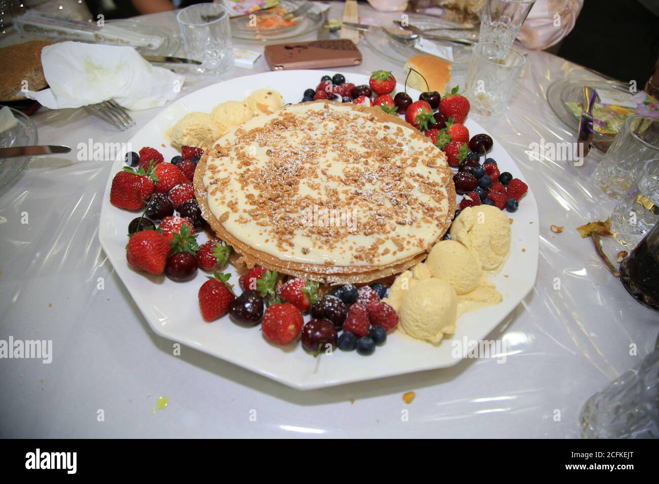 Close-up deliziosi pancake con mirtilli freschi, fragole e sciroppo d'acero su uno sfondo luminoso. Con copia spazio. Dolce di sciroppo di acero fluisce dal Foto Stock