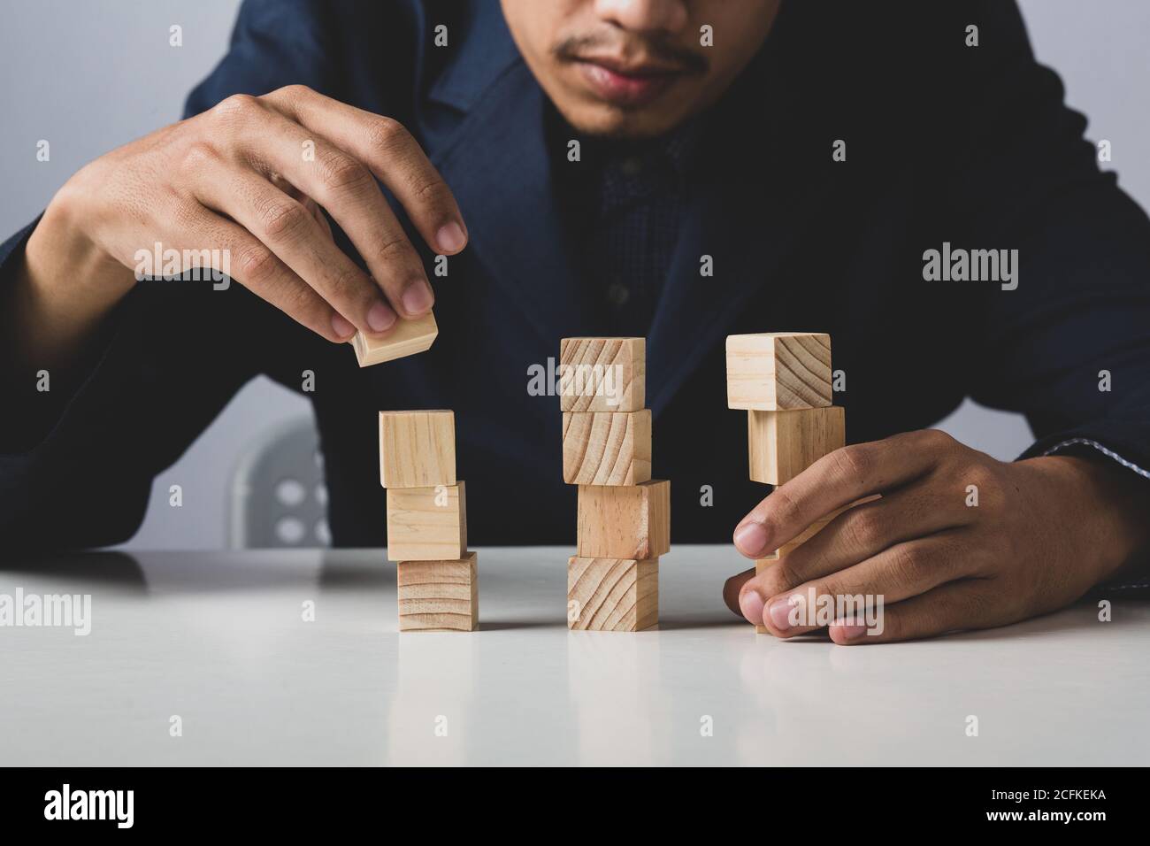 Mani di imprenditore uomo d'affari che tiene blocchi di legno che mettono ad una struttura, concetto di lavoro di squadra, strategia, lavoro professionale di manager per executiv Foto Stock