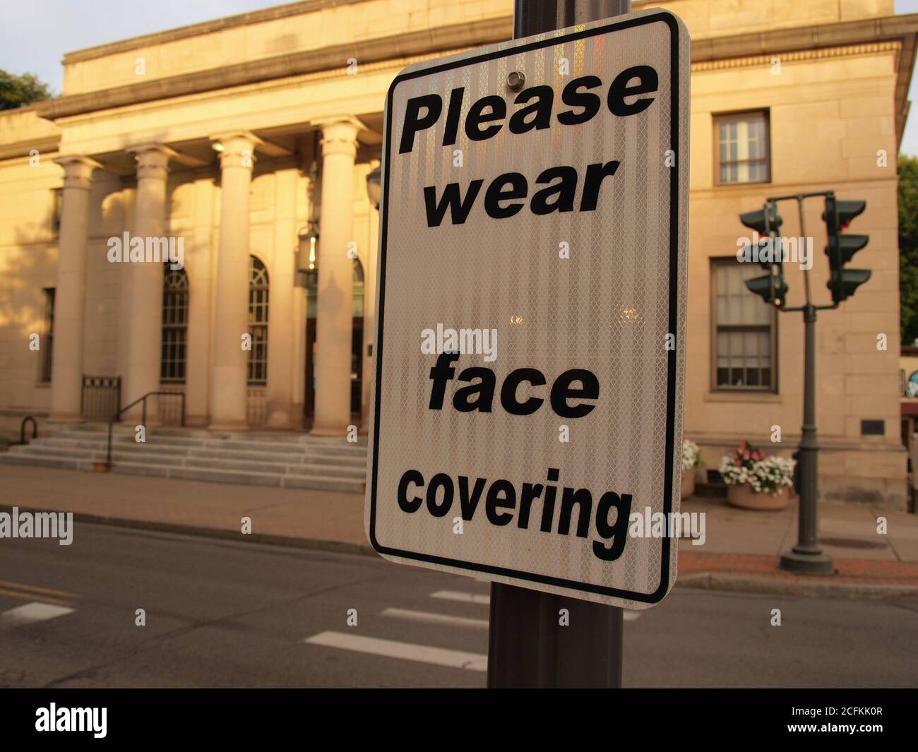 Un cartello dell'era Covid su una American Main Street chiede ai cittadini di indossare maschere contro la diffusione della malattia, dicendo: "Si prega di indossare la copertura facciale" Foto Stock
