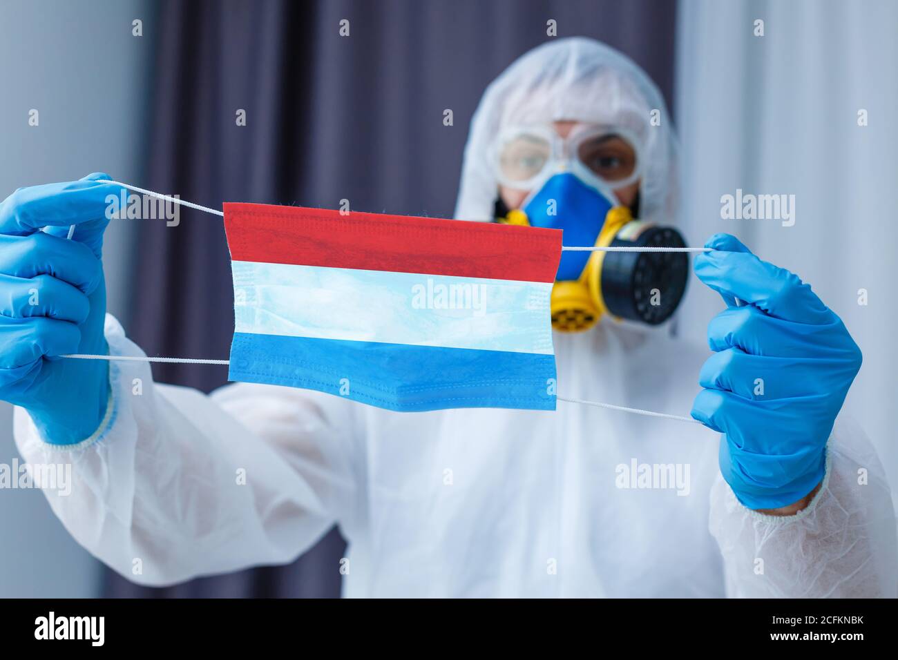 Medico maschile, disinfettante in tuta protettiva, respiratore, occhiali di protezione, bandiera nazionale olandese, concetto di armi biologiche e chimiche, coronavirus Foto Stock