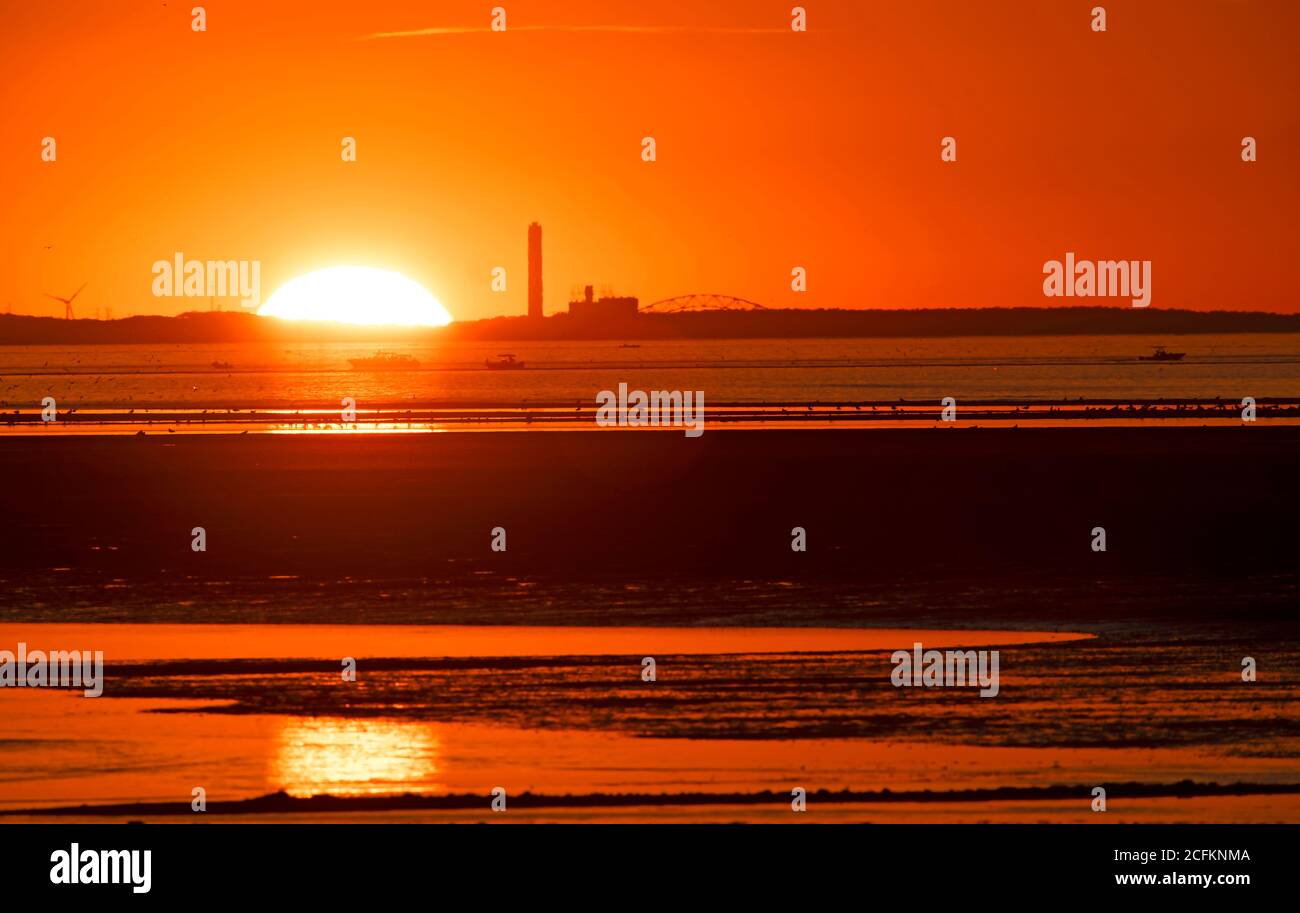 Il sole tramonta dietro una centrale a Cape Cod in una serata estiva. Foto Stock