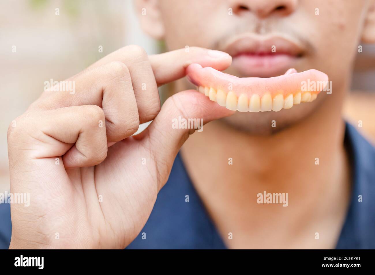 Un uomo sta tenendo le dentiere nelle sue mani. Protesi rimovibili flessibili. Denti falsi. Foto Stock