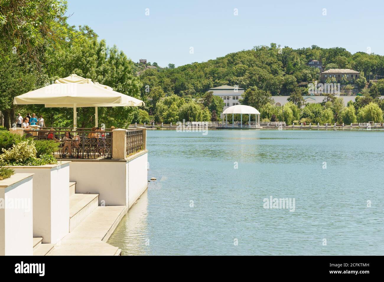 Russia, regione di Krasnodar, Novorossiysk, Abrau-Durso - 12 giugno 2018: La gente siede in un caffè estivo sulla riva del lago Abrau nel villaggio di resort - Th Foto Stock